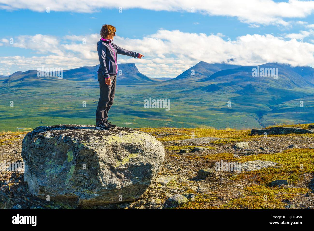Woman standing on a rock on Mount Nuolja with Lapporten, Tjuonavagge in background, pointing at Lapporten, Abisko, Swedish Lapland, Sweden Stock Photo