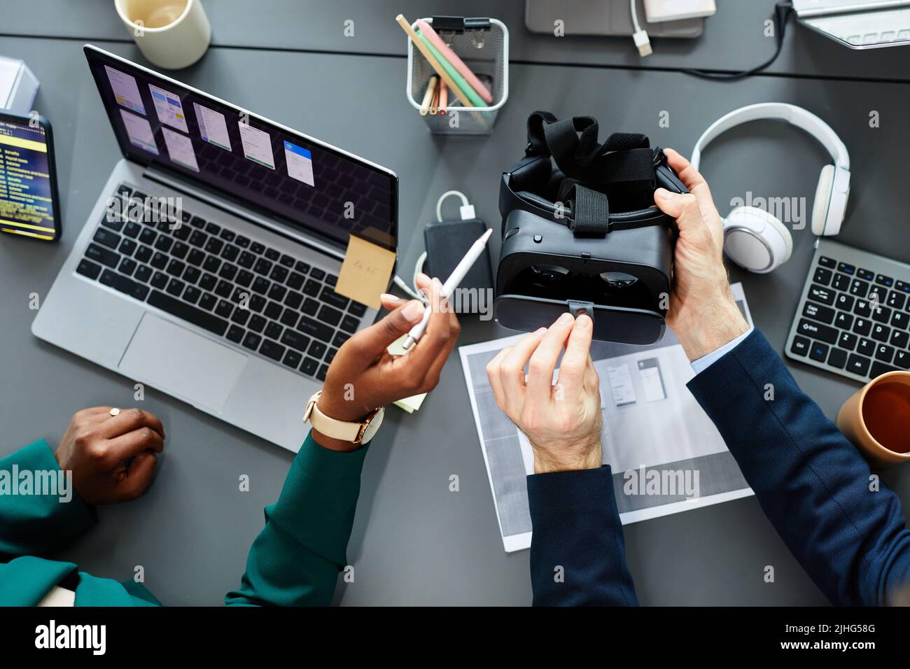 High angle view of programmers testing new virtual reality glasses at table using laptop and smartphone Stock Photo