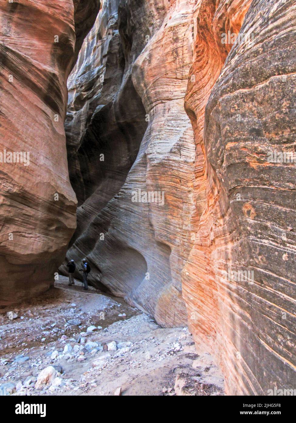Two hikers, deep within one of the narrow Slot Canyons of Willis Creek in Utah, USA, Stock Photo