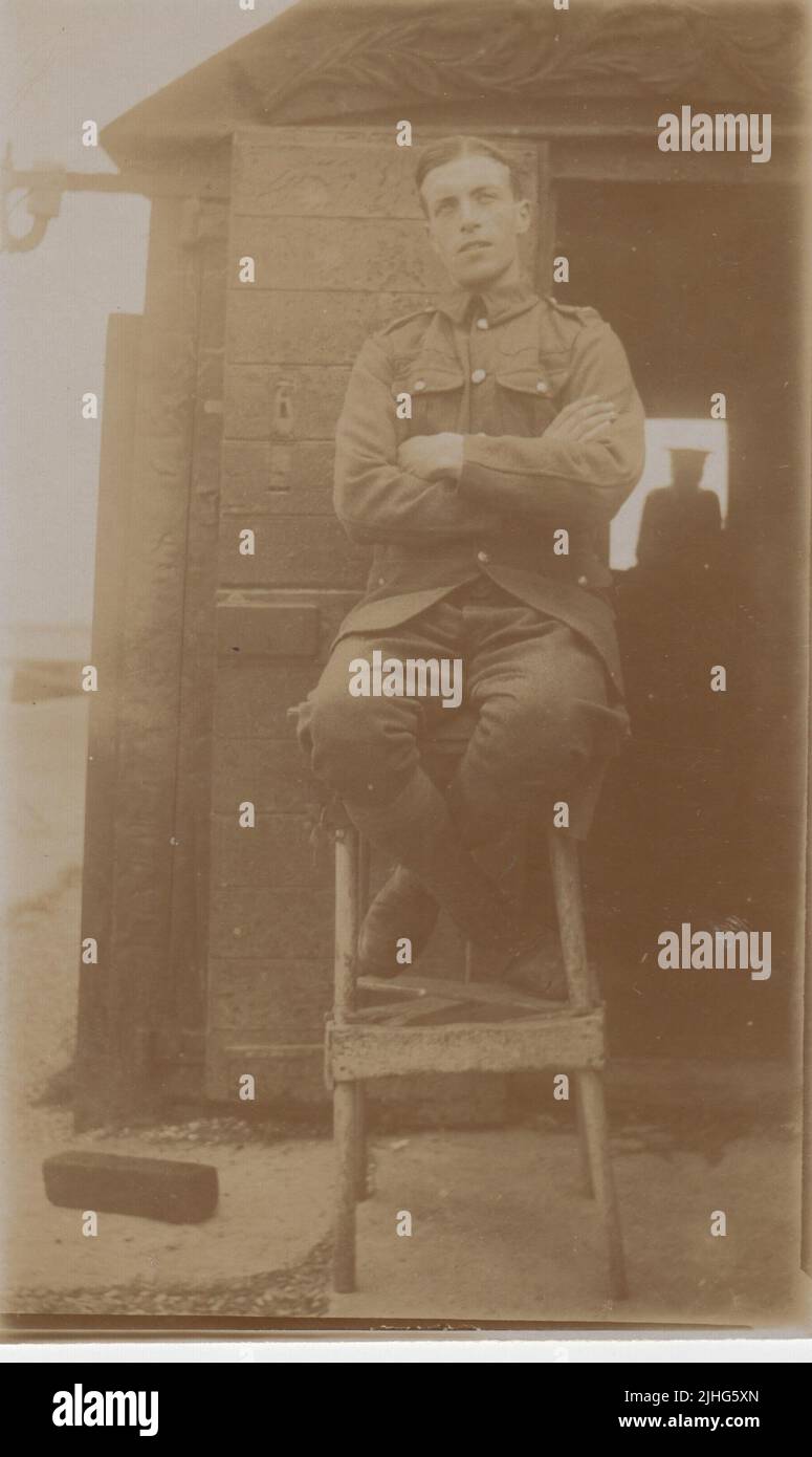 Soldier in the Kent Cyclist Battalion, photographed sitting with arms folded outside a hut on 1 September 1915. The silhouette of another soldier can be seen inside the hut Stock Photo