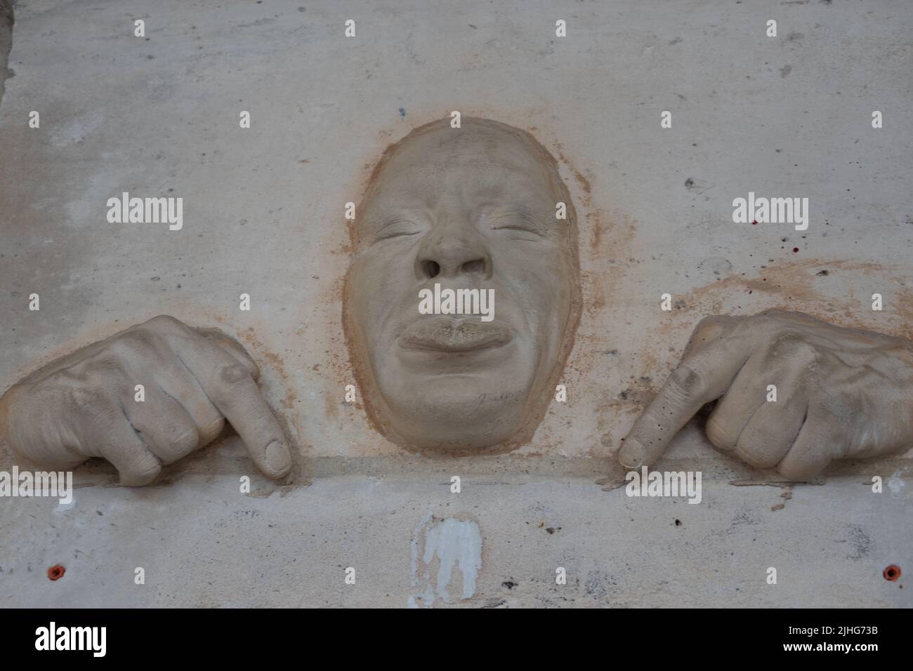 Stone carving on a fat face with pouting lips and hands with fingers pointing down Paris Francw Stock Photo