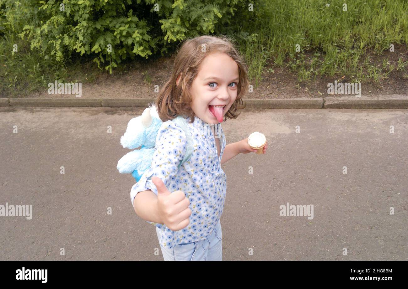 Funny blond blue eyed girl with ice cream stuck out tongue, shows Like