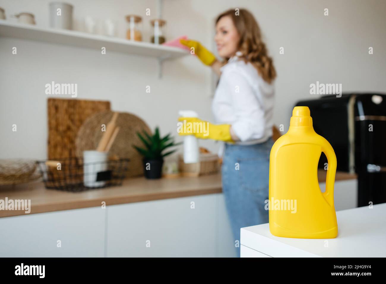 Beautiful girl wipes the shelves in the kitchen Stock Photo