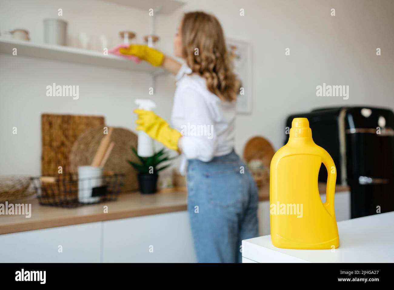Beautiful girl wipes the shelves in the kitchen Stock Photo