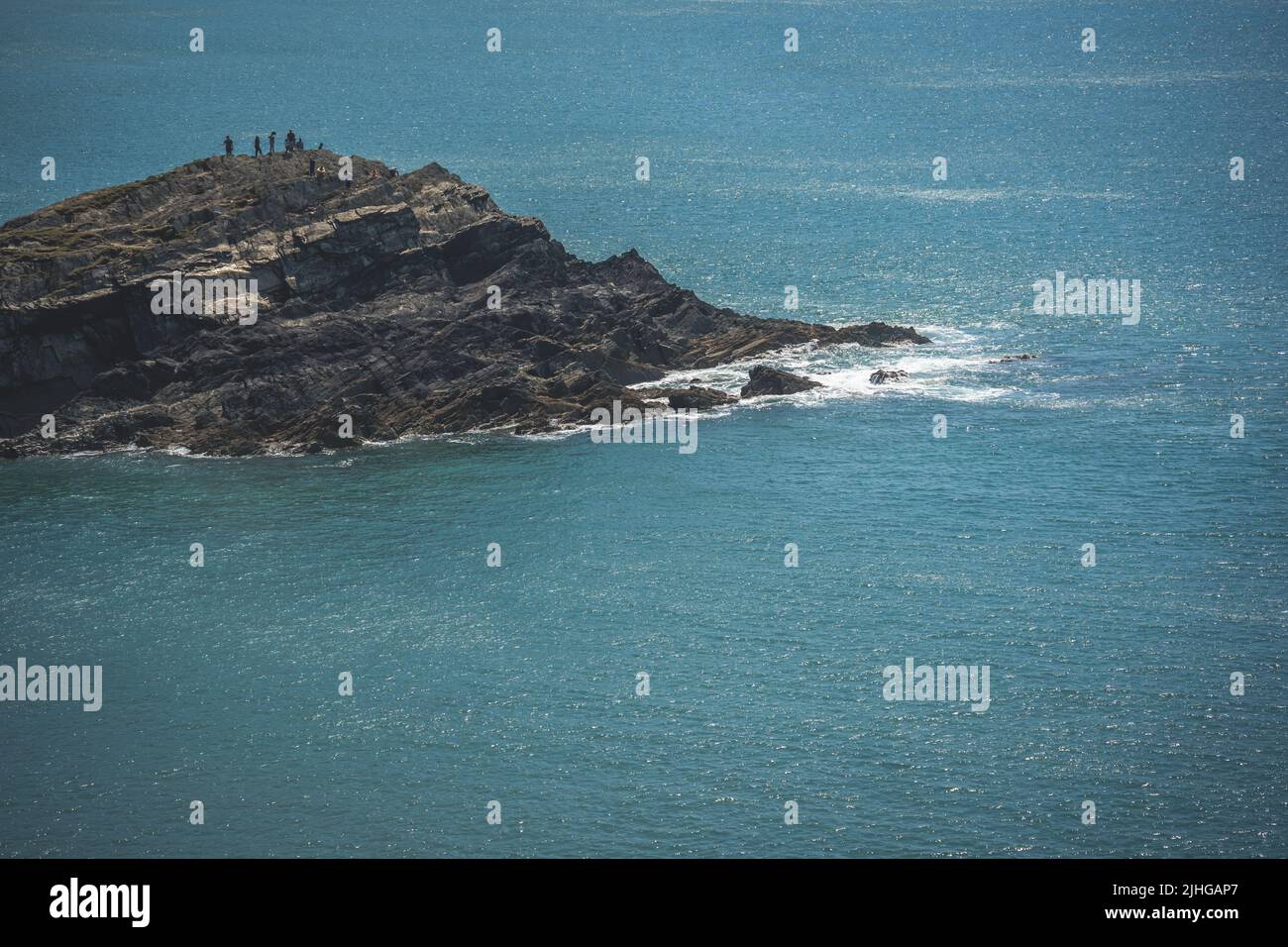 Tenby, Wales - May 2021 : People standing on top of a huge rocky outcrop enjoying hot summer day on The Whitesands Bay beach and cliffs Stock Photo