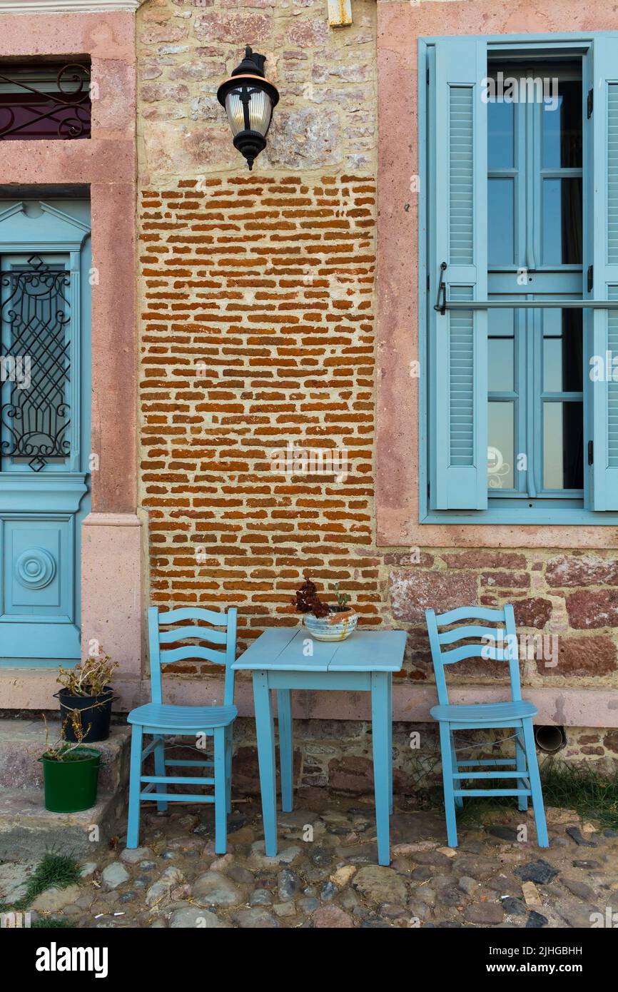 View of old, historical, traditional house in famous, touristic Aegean town called Cunda. It is a village of Ayvalik, Turkey. Blue chairs and table re Stock Photo