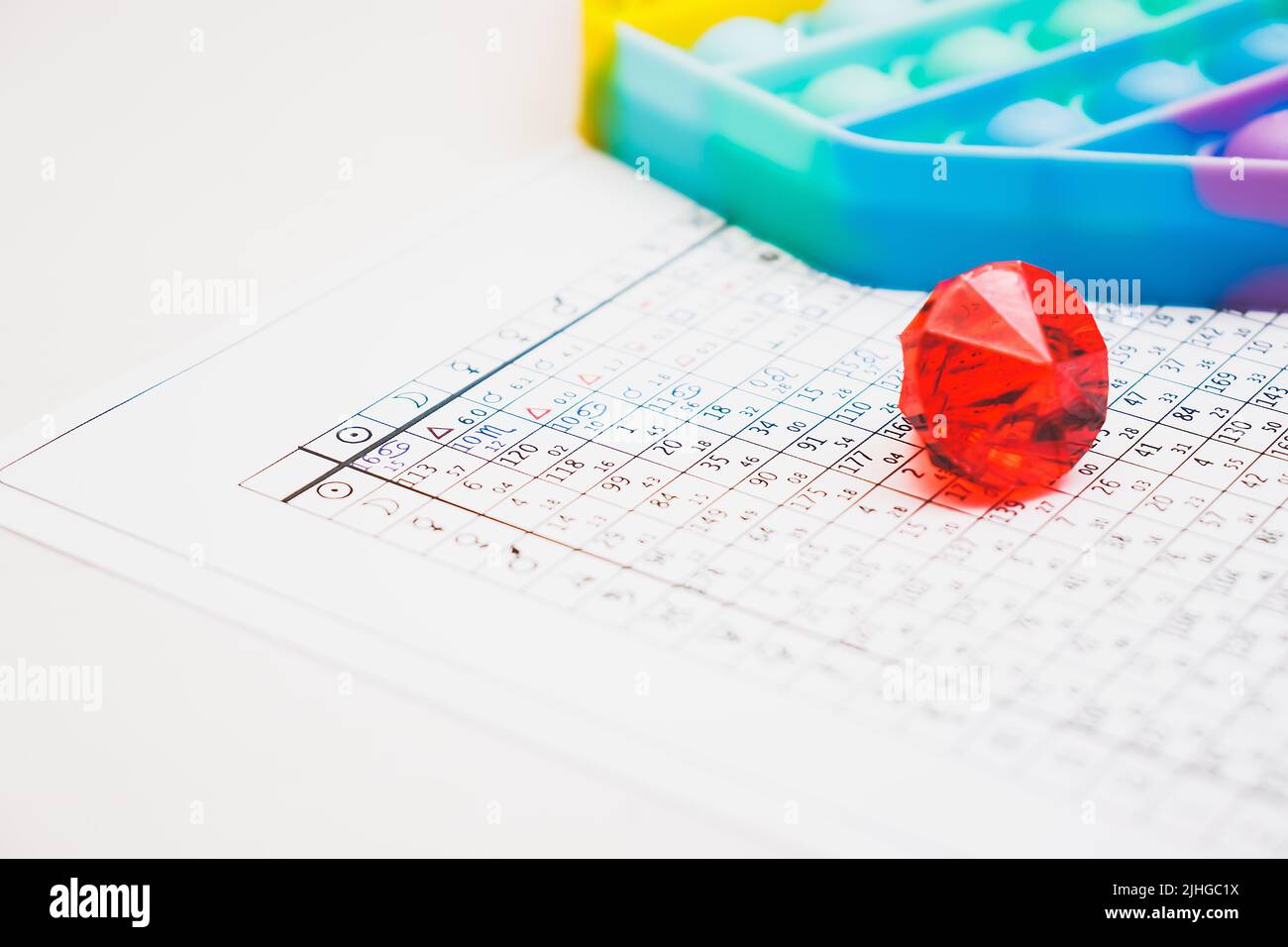 Modern astrologer's desktop. Pop it and a red glass pebble on the table. Astrological charts and tables with the coordinates of the planets, astrologi Stock Photo