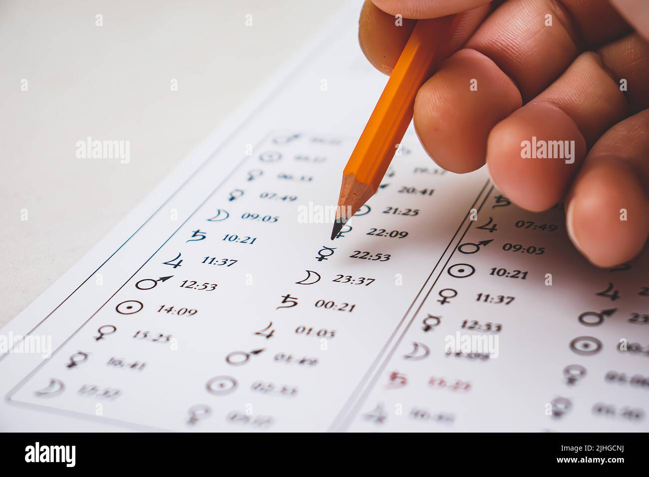 Modern astrologer's desktop. Hand with a pencil. Astrological charts and tables with the coordinates of the planets, astrological symbols close-up. Stock Photo