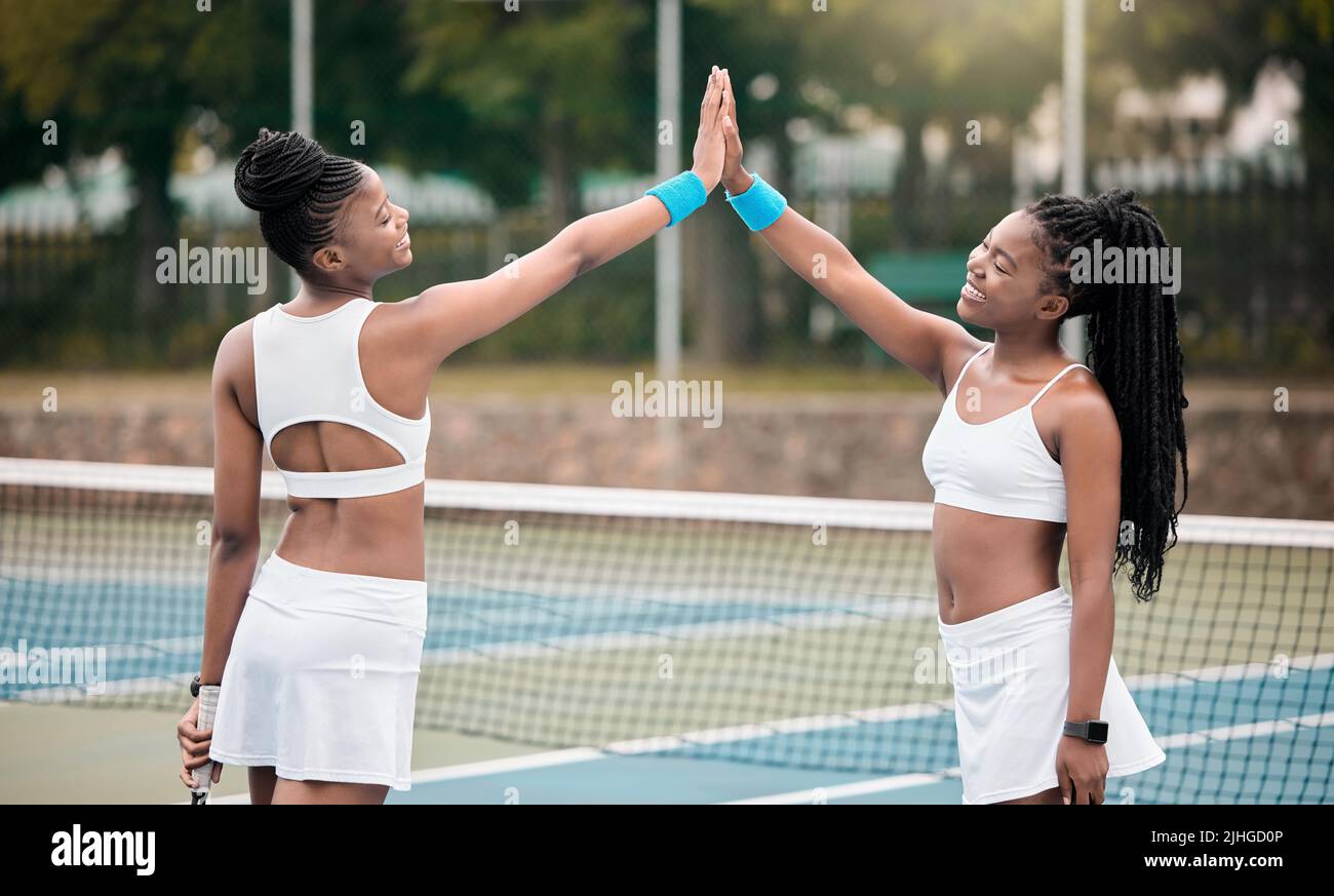Happy friends high five on the tennis court. Two professional tennis players motivate each other after a match. African american girls bonding Stock Photo