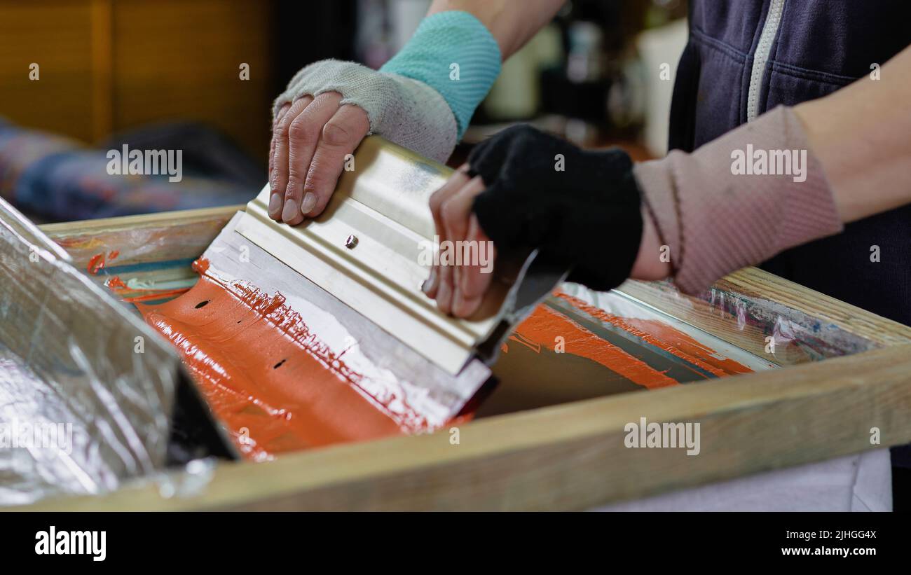 male hands with a squeegee. creating print on tshirt in