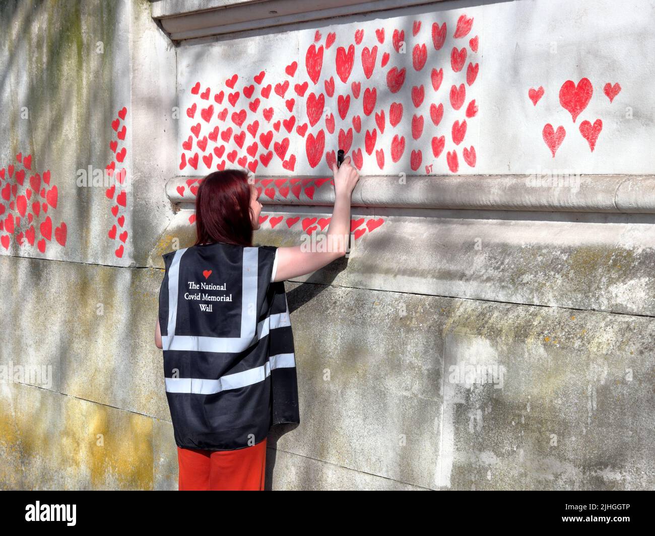 London, UK - March 30, 2021: The National Covid Memorial Wall, volunteers painting 150,000 red hearts to commemorate Covid-19 deaths Stock Photo