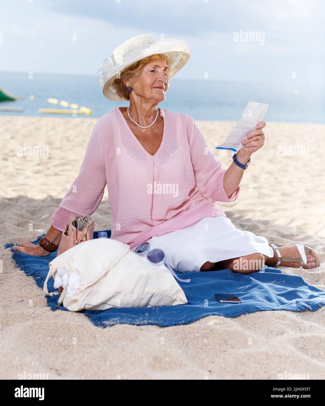Elderly woman relaxing on beach Stock Photo - Alamy