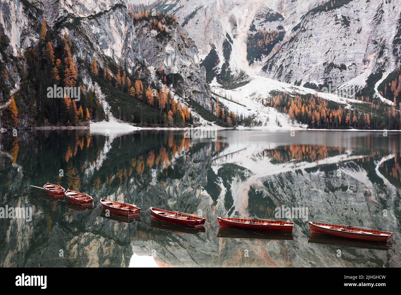 Picturesque landscape with famous lake Braies in autumn Dolomites mountains. Wooden boats and pier in clear water of Lago di Braies, Dolomite Alps, Italy. Seekofel mountain peak on background Stock Photo