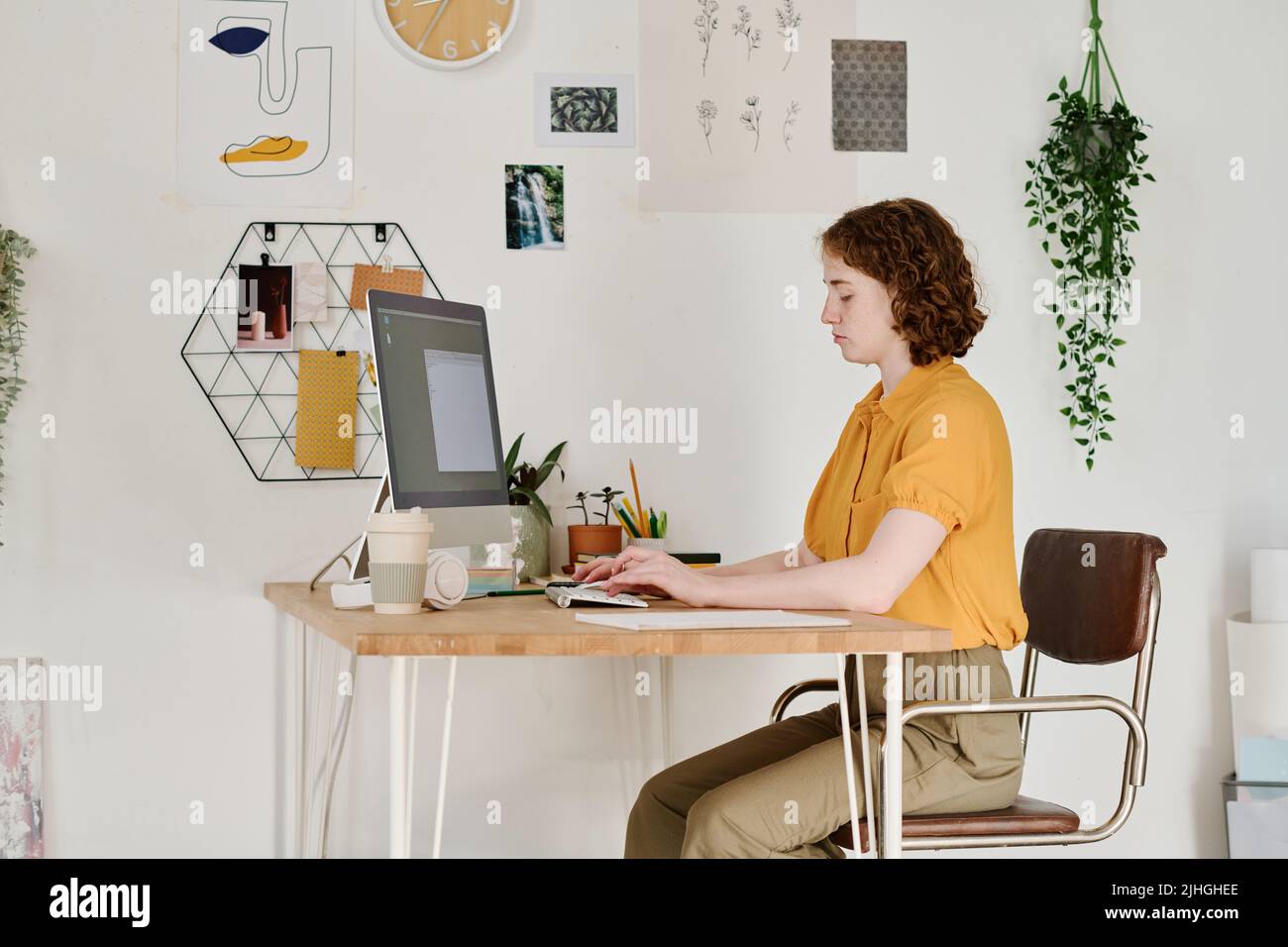 Young serious female freelancer or webdesigner concentrating on work over creation of new website while sitting in front of computer Stock Photo