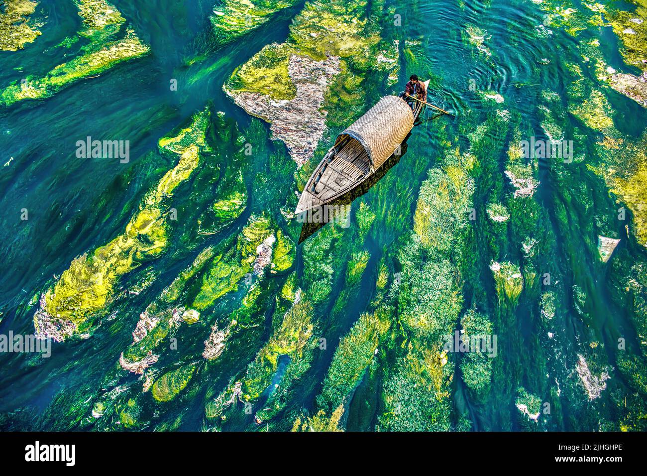 People boating in algae and water plant covered river in Bogura, Bangladesh Stock Photo