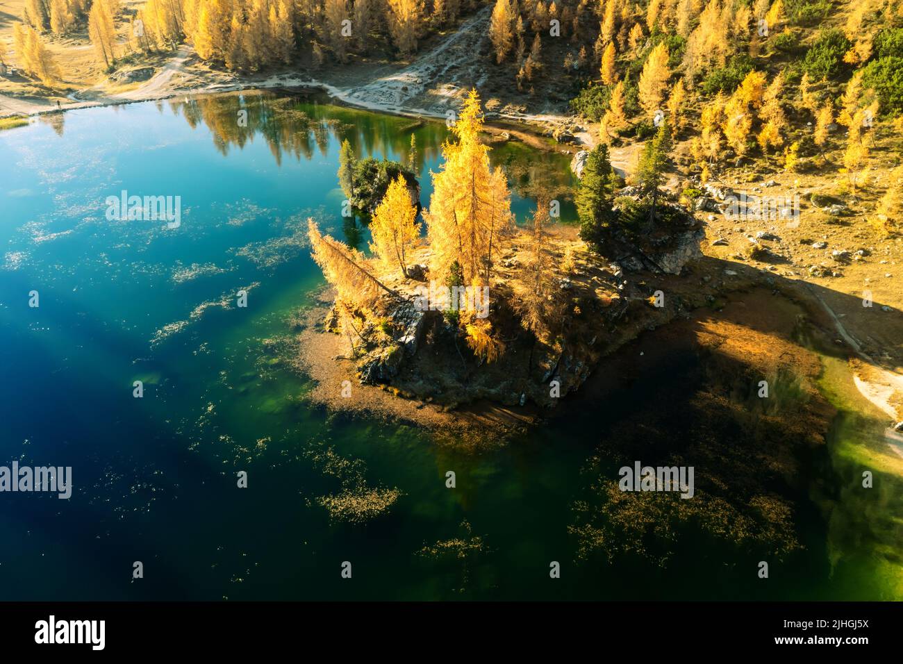 Drone flight over Federa Lake in sunrise time. Autumn mountains landscape with Lago di Federa and bright orange larches in the Dolomite Apls, Cortina D'Ampezzo, South Tyrol, Dolomites, Italy Stock Photo