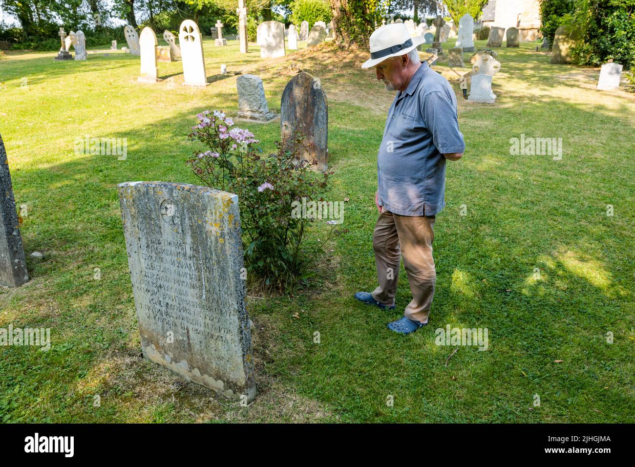 Older man wearing a Panama hat looking at Georgi Markov gravestone, Bulgarian dissident, Whitchurch Canonicorum churchyard, Dorset, England, UK Stock Photo