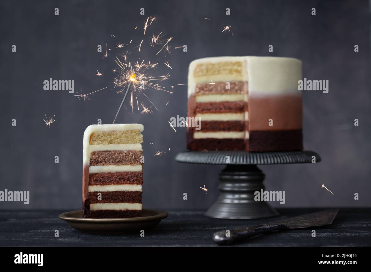 Chocolate ombre birthday cake with slice of birthday cake decorated with a celebration sparkler Stock Photo