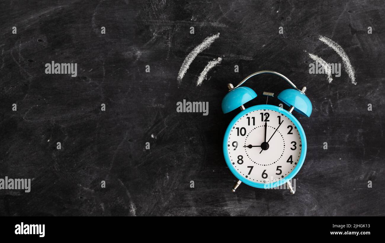 Twin bell alarm clock ringing against a chalkboard with copy space to side Stock Photo
