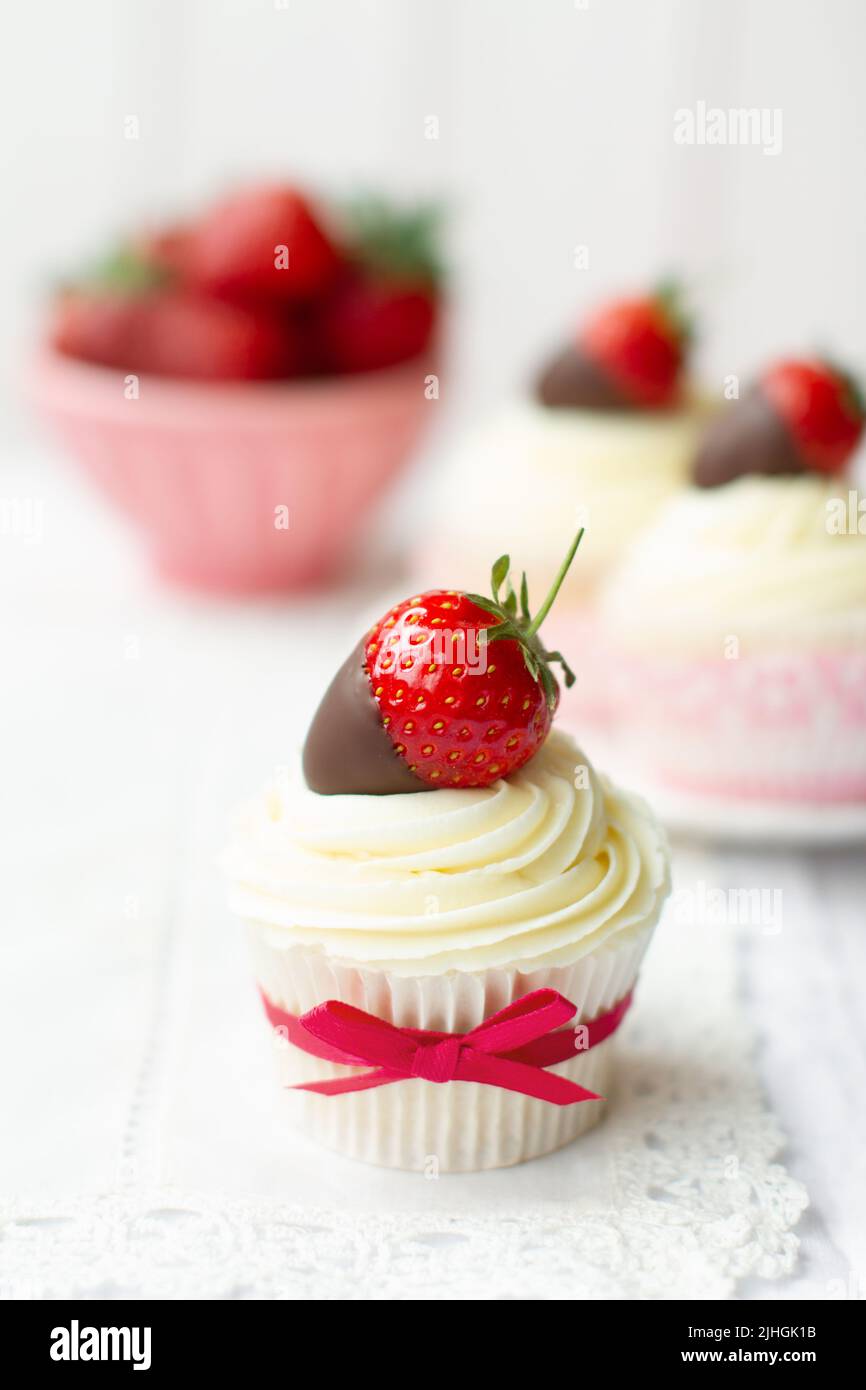 Cupcakes decorated with whipped cream and chocolate dipped strawberries Stock Photo