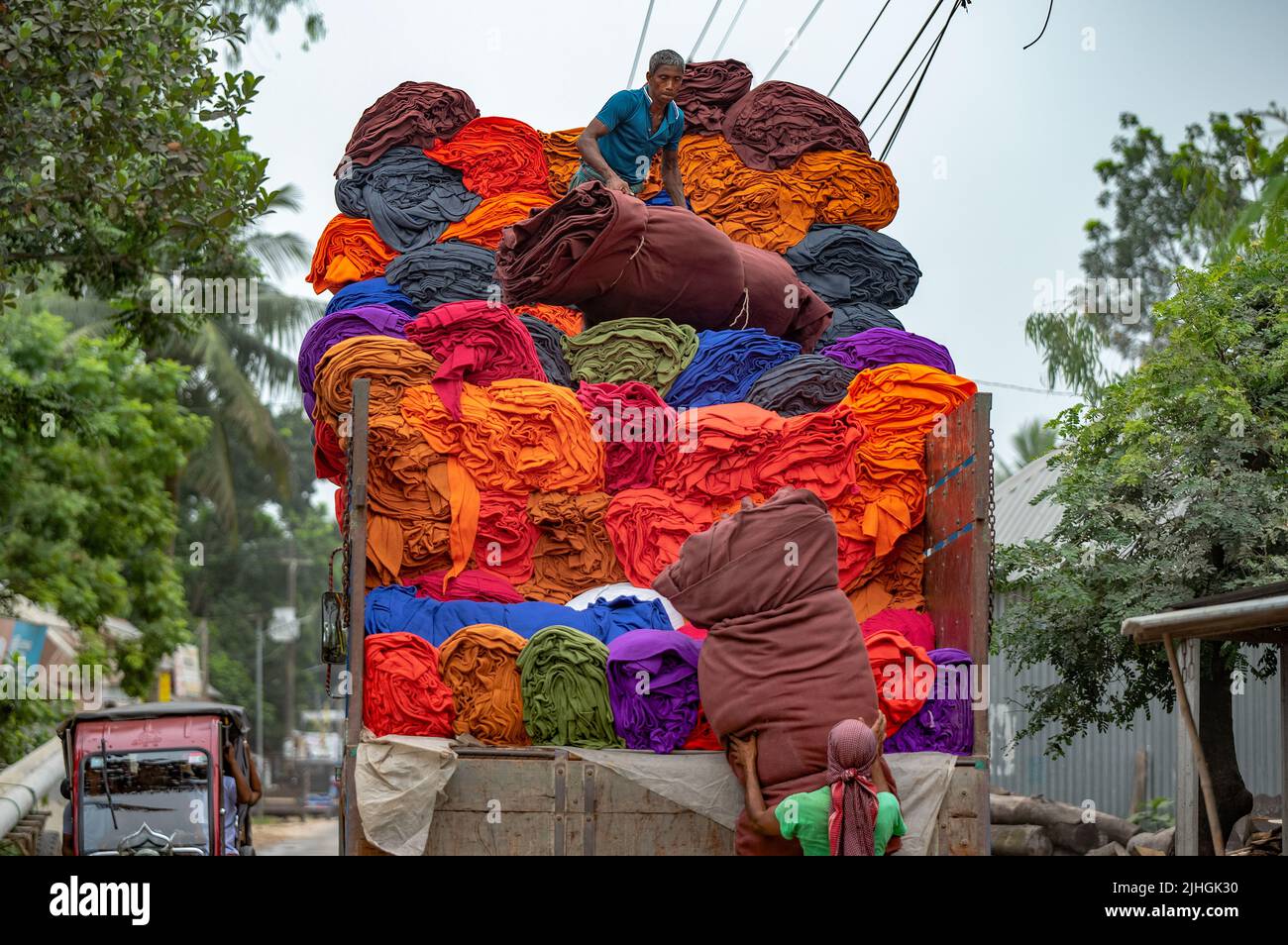 Colorful blankets are being loaded to trucks by workers. Textile