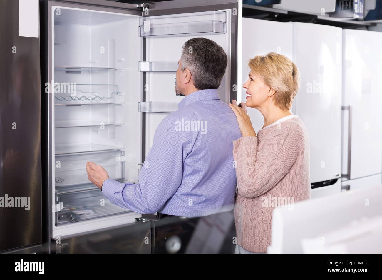 Mature woman with husband chooses refrigerator Stock Photo