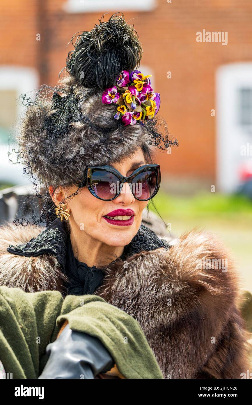 Head and shoulder portrait of a senior woman dressed up in 1940's glamorous clothing, fur collar, fur hat with lace and large sunglasses. Stock Photo