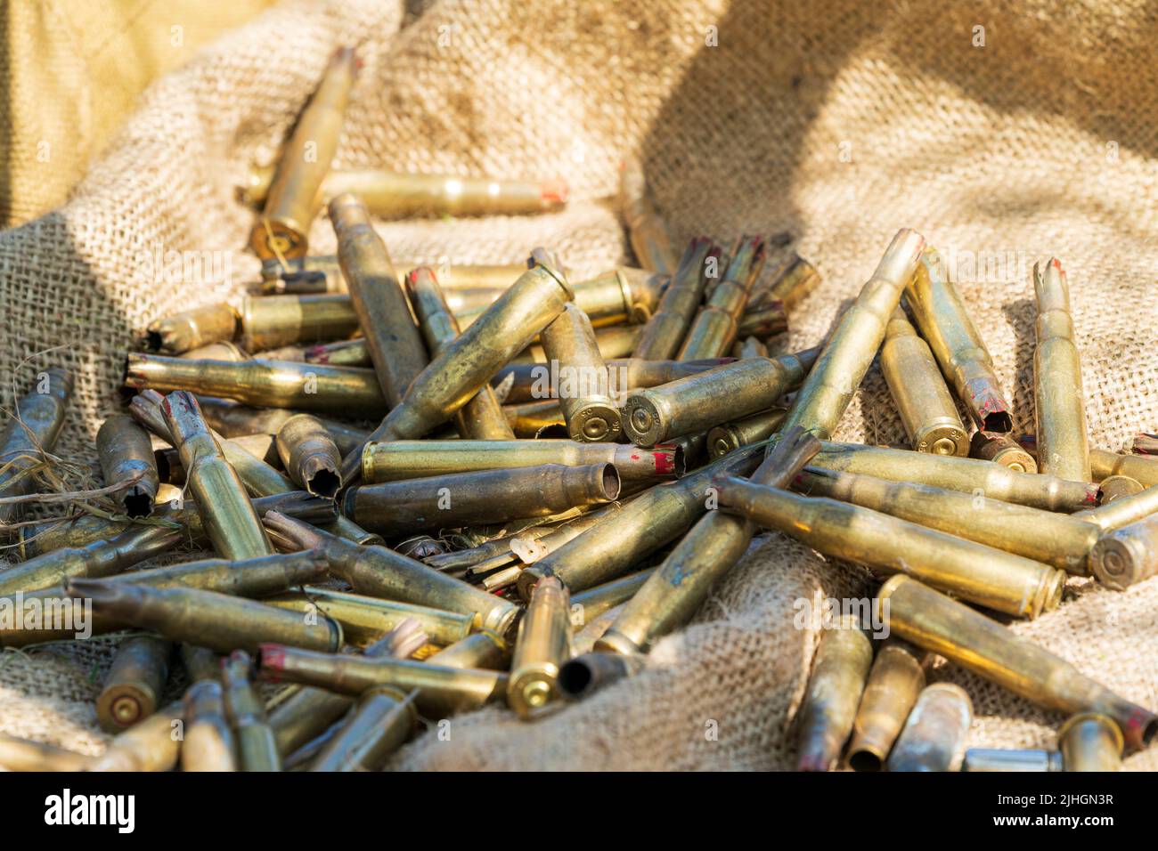 Pile of spent 7.62mm bullet casings, ammunition, on a canvas sheet in bright sunlight. 'Salute to the forties' reenactment. Stock Photo