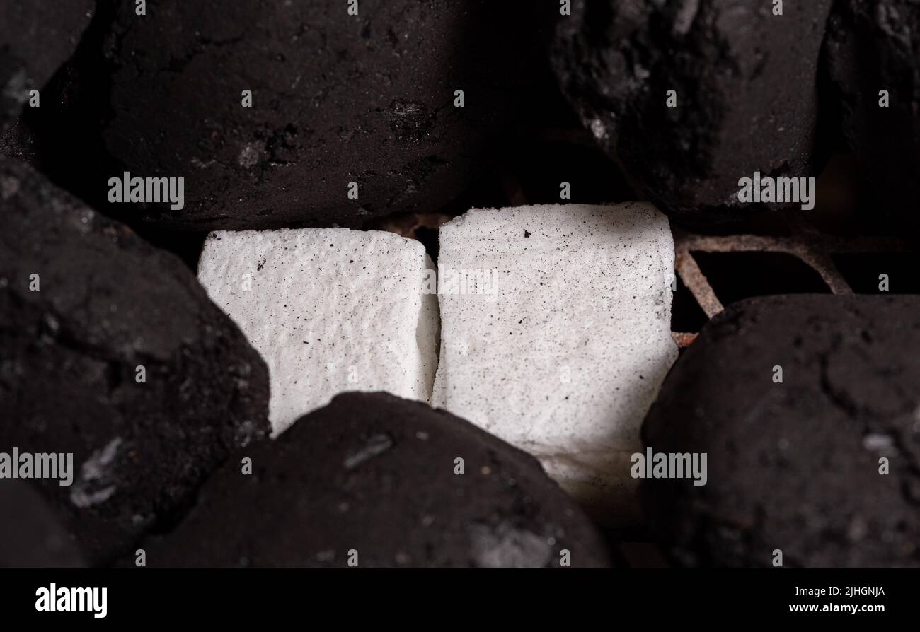 Lighting a barbecue fire. Briquette and white cube grill lighter. Flame