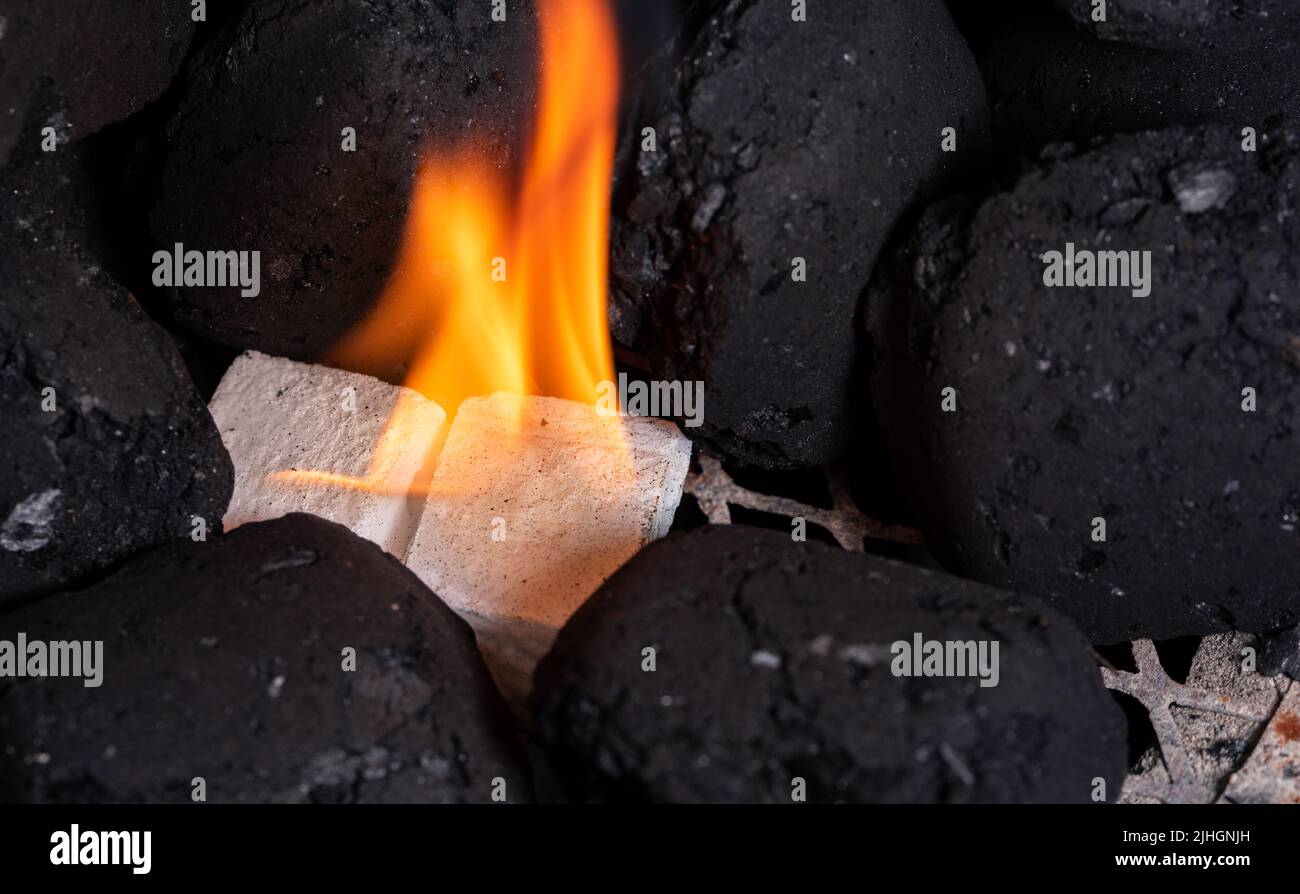 Lighting a barbecue fire. Briquette and white cube grill lighter. Flame