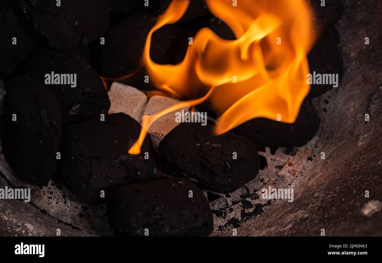 Lighting a barbecue fire. Briquette and white cube grill lighter. Flame