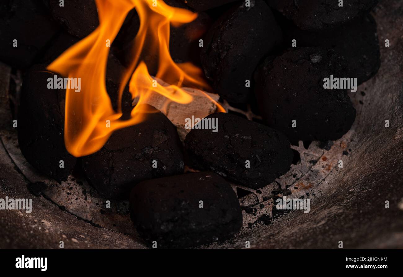 Lighting a barbecue fire. Briquette and white cube grill lighter. Flame