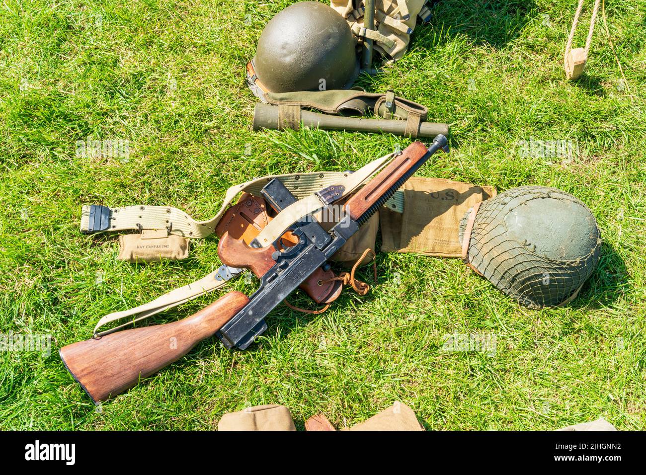 Second world war US army equipment laying on grass. Thompson submachine gun (tommy gun), helmet, belt, and ammo pouches. Stock Photo
