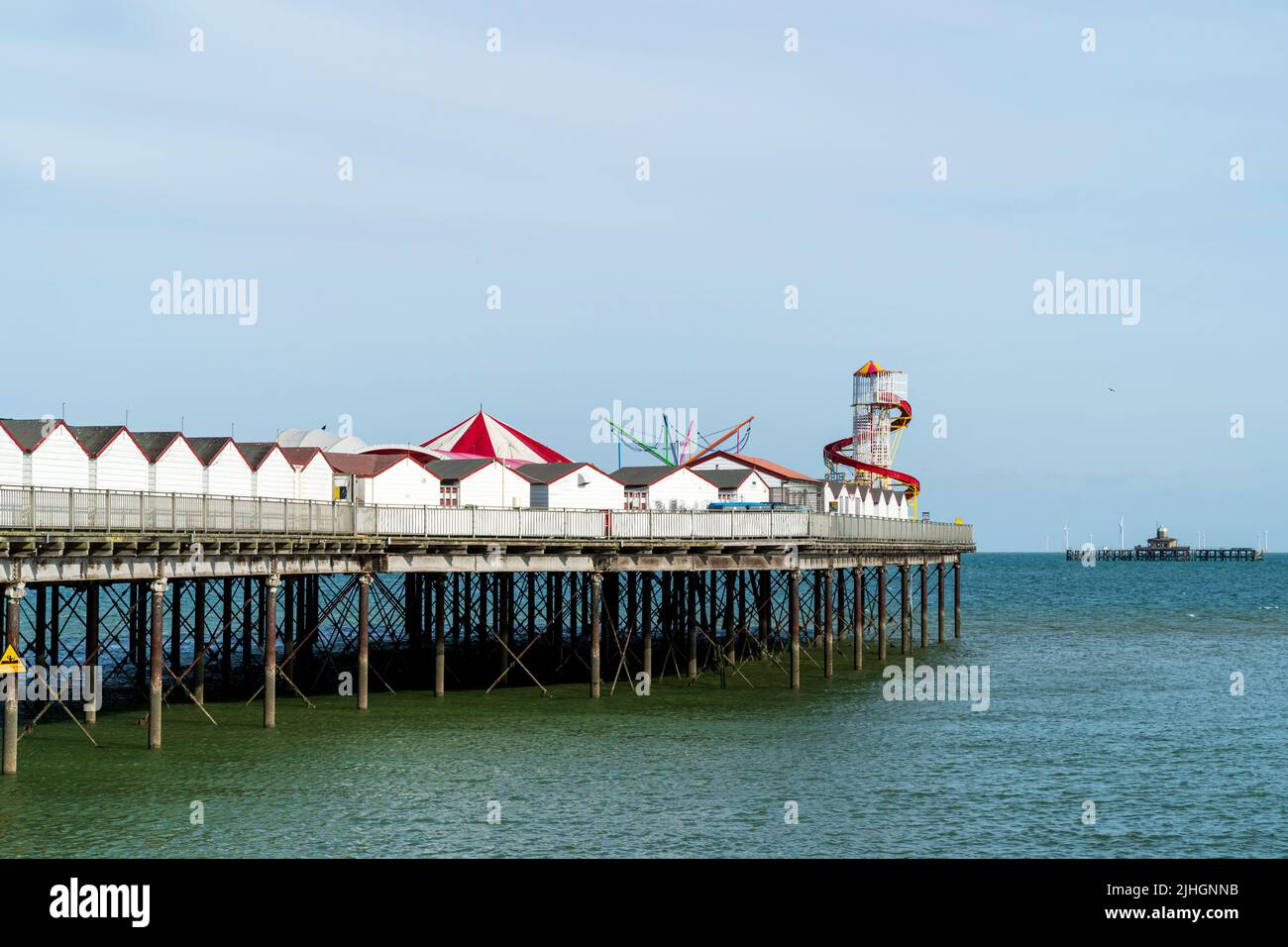 The pier at the Kent resort town of Herne Bay. White wooden chalet retail units along the length with a helter skelter at the end. Summertime. Stock Photo