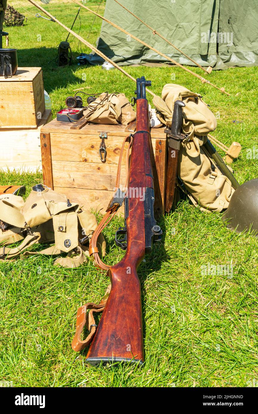 Second world war English army equipment propped up on wooden box on grass. Lee-Enfield rifle, bags and knife. Stock Photo