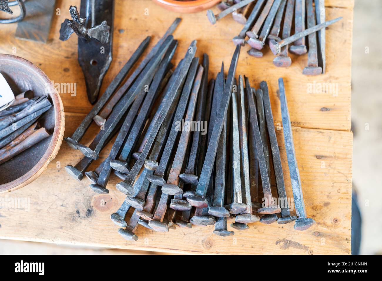Pile of medieval nails on wooden bench at the Sandwich Medieval center. Stock Photo