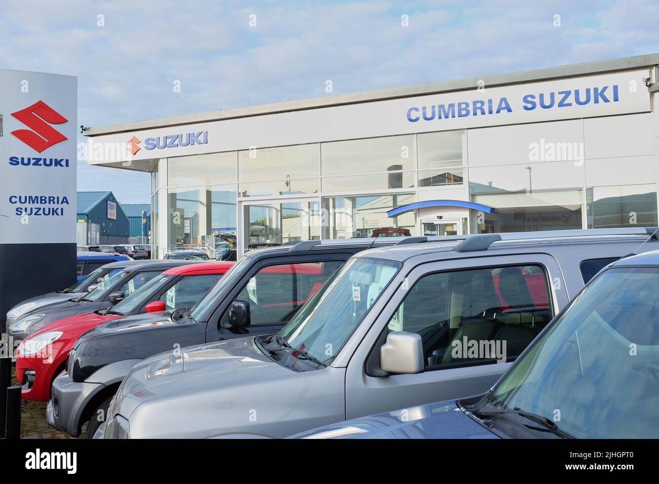 Forecourt of Cumbria Suzuki showing various Suzuki cars for sale in front of modern car showrooms. Stock Photo