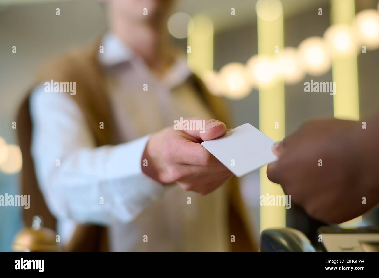 Hand of young male travler or guest of hotel taking keycard held by African American female receptionist after registration Stock Photo