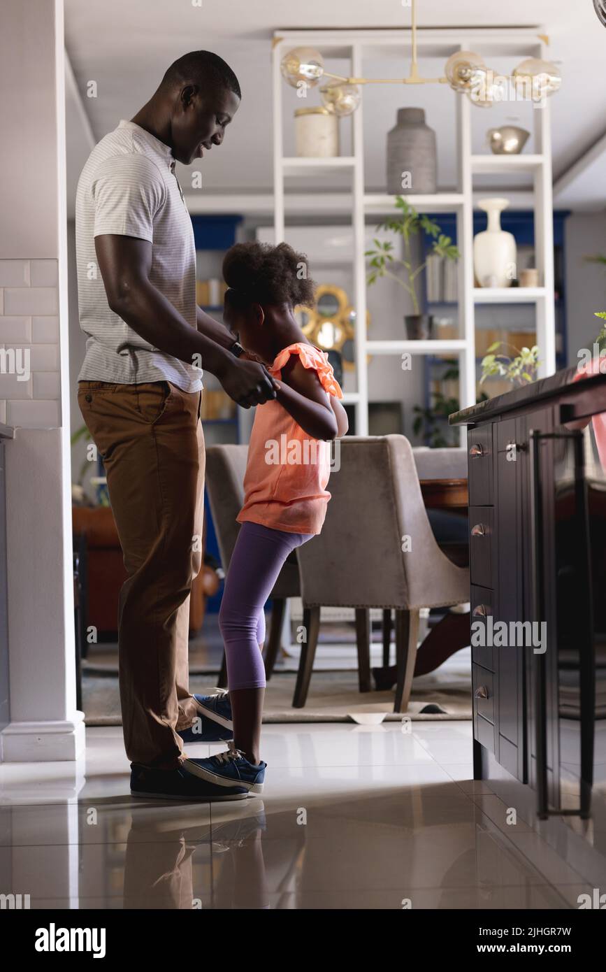 Vertical image of african american father and daughter dancing in kitchen Stock Photo