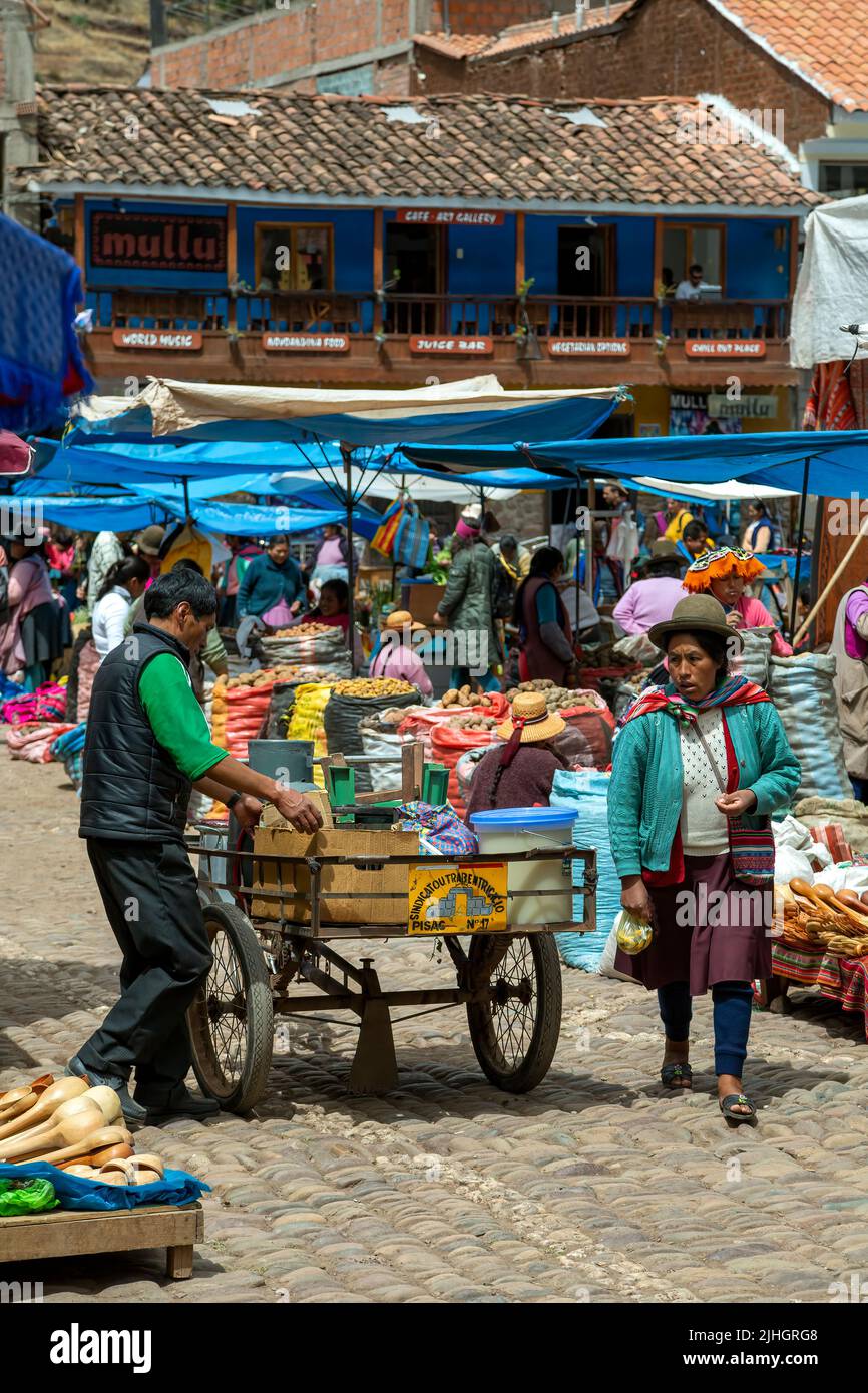 Man, cart, Quechua woman and vendor stalls, Pisac Sunday Market, Cusco, Peru Stock Photo