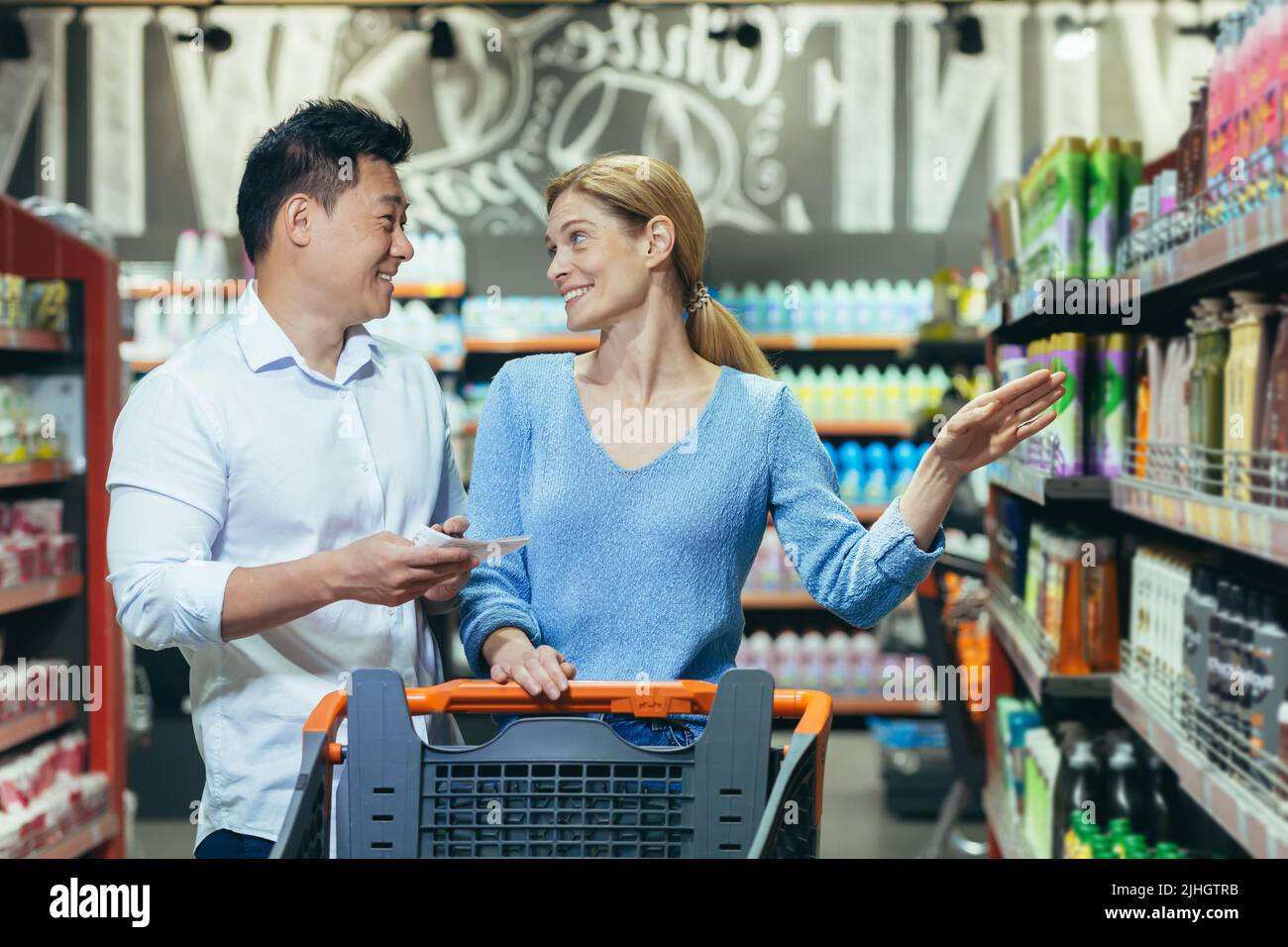 Happy shoppers Asian man and woman buy and choose goods in supermarket, family shopping Stock Photo