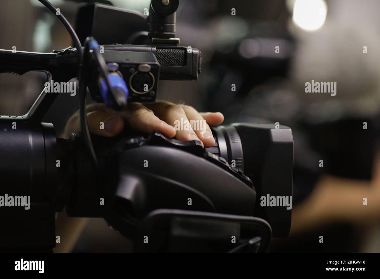 Shallow depth of field (selective focus) details with the hands of a news camera operator using buttons of his camera during a press event. Stock Photo