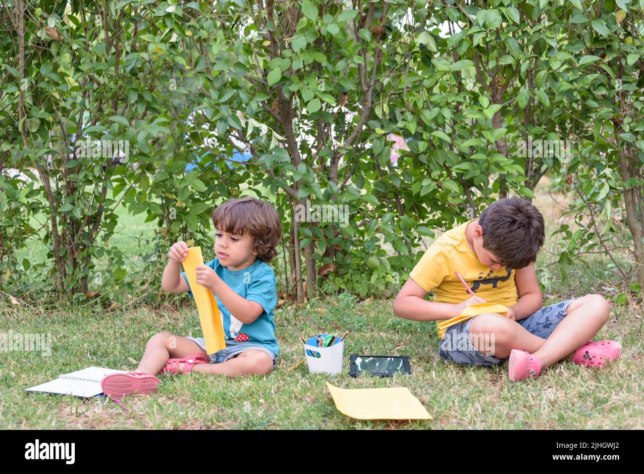 Back to school. Two happy and cheerful children, a schoolboy with notebooks and paints in their hands in the park. Stock Photo