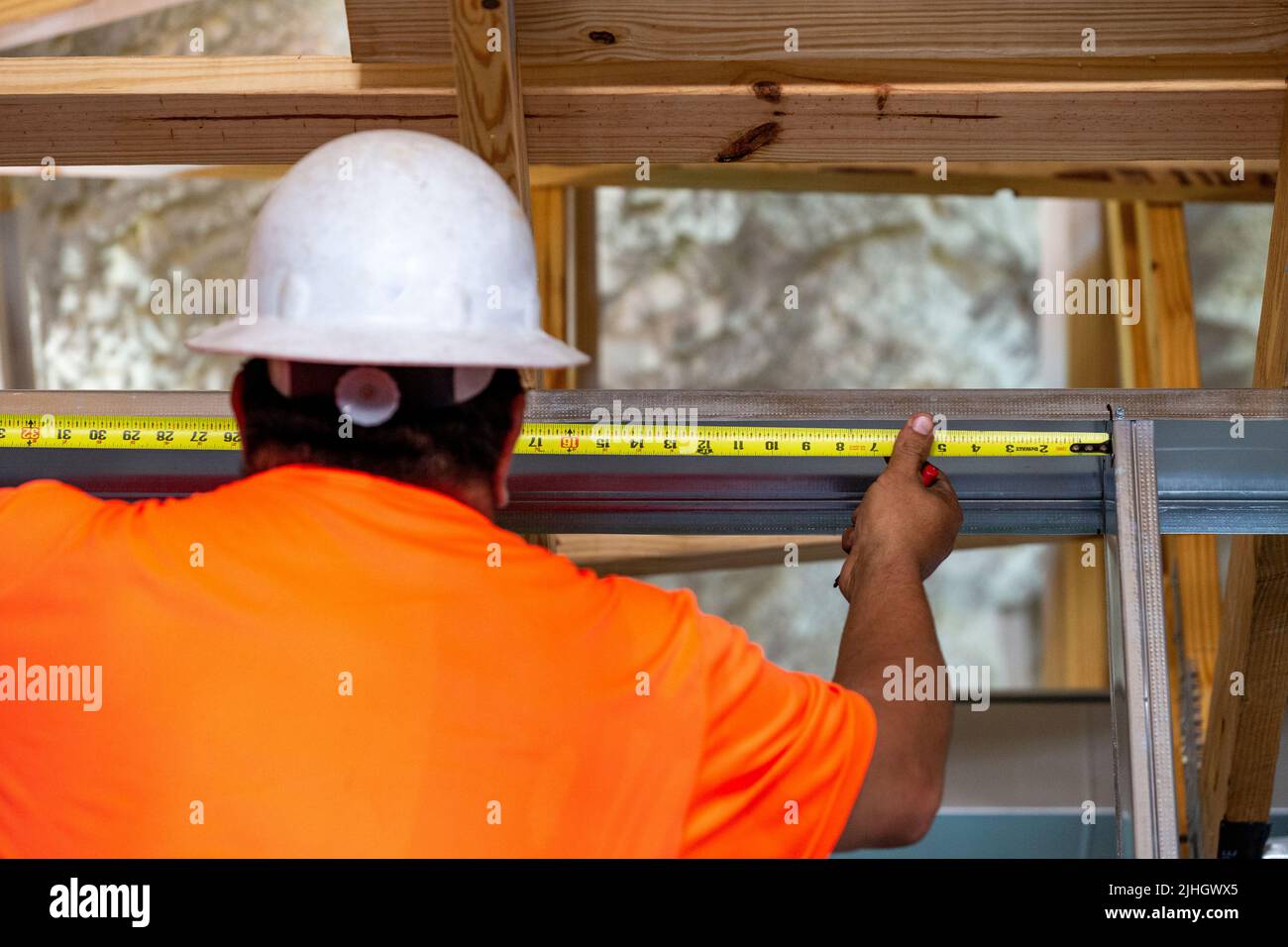 A construction worker, framer measuring a horizontal space of