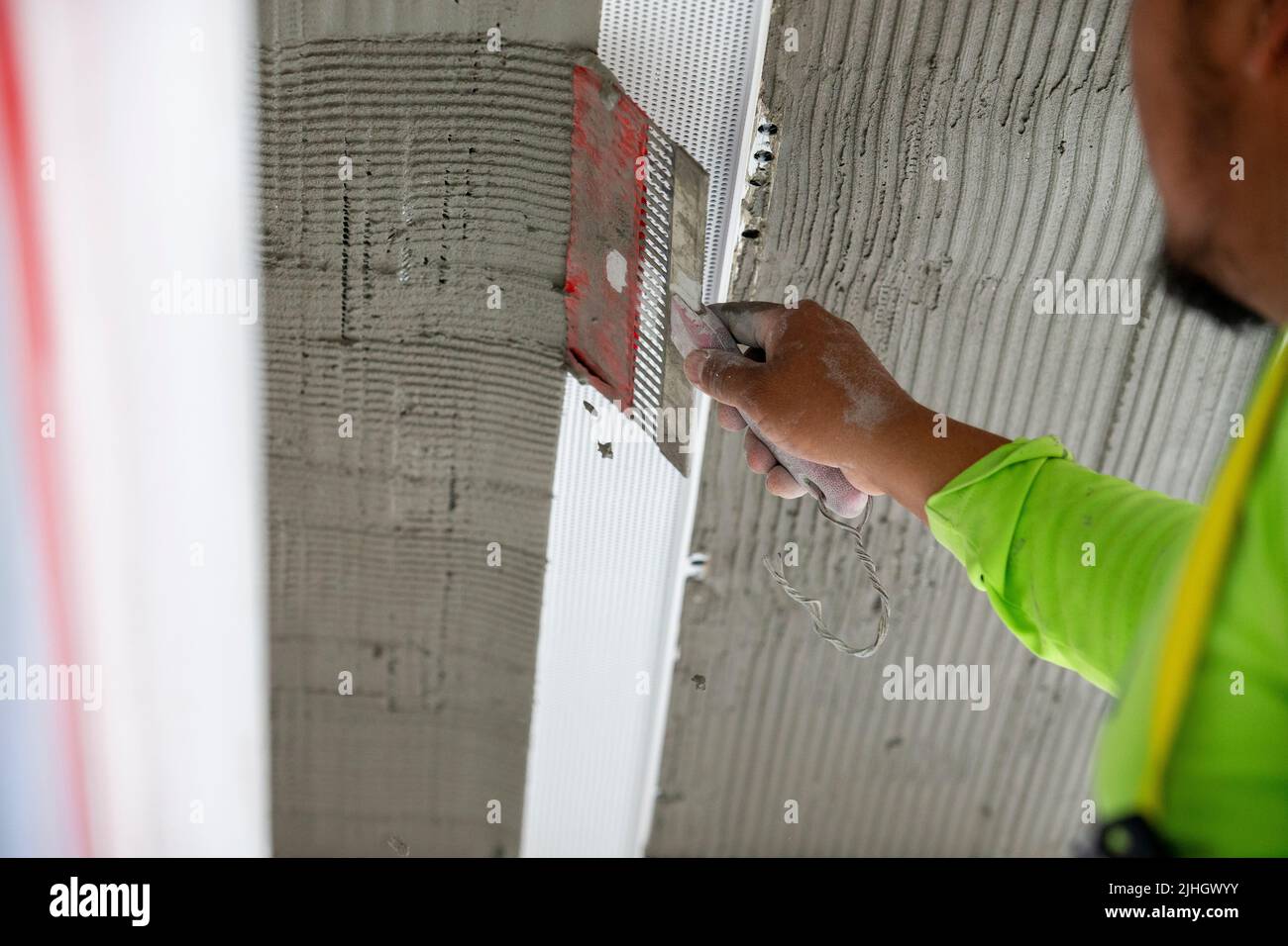 Construction worker using a notched trowel to rake the stucco mud for