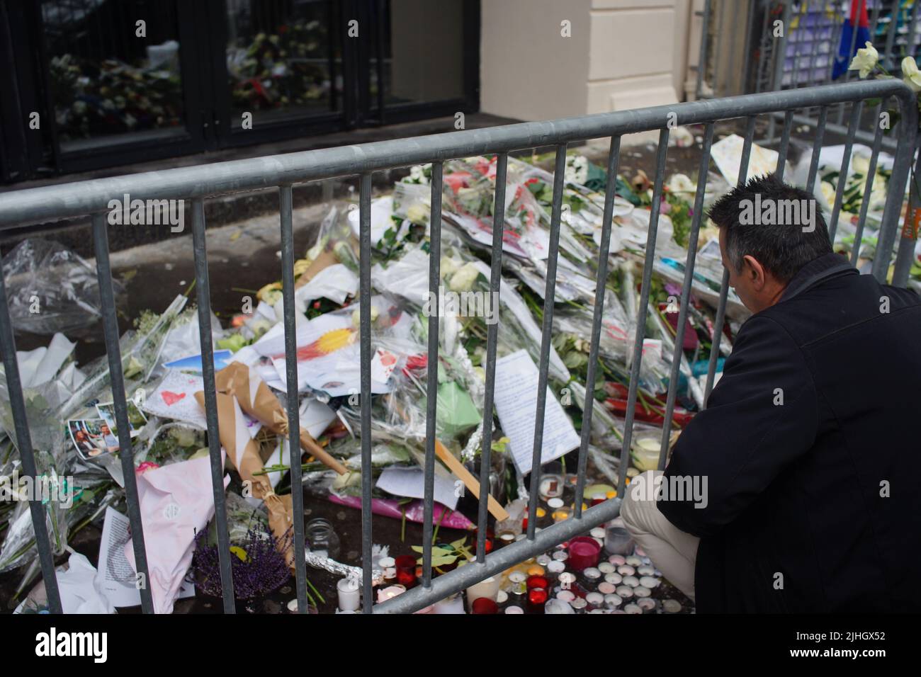 Man looks at flowers, candles and messages outside the Bataclan music venue, Paris, to commemorate victims of November 2015 Paris attacks. Le Bataclan, 50 Boulevard Voltaire, Paris, France - Paris terror attacks - one year on Stock Photo