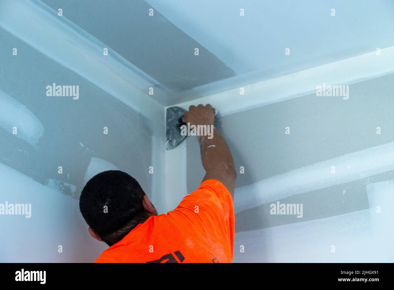 skilled construction worker is pulling a spatula over drywall finishing ...