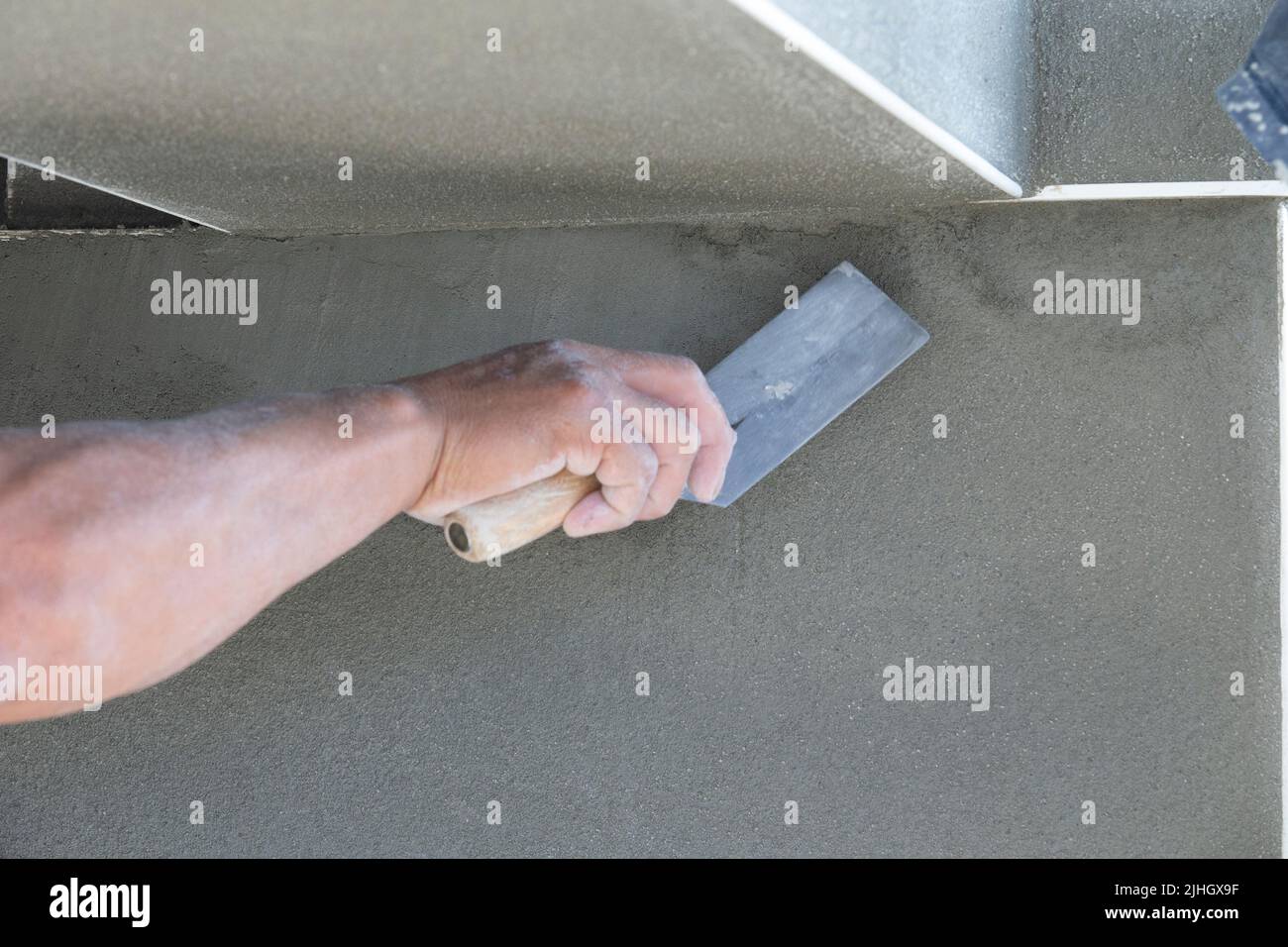 Skilled construction worker finishing a wall of stucco with a trowel and smoothing out little uneven areas. Affordable Housing Stock Photo