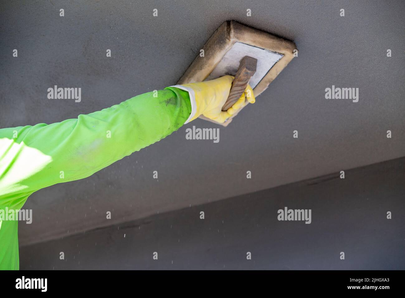 Construction worker using a wet sponge trowel to smooth out freshly