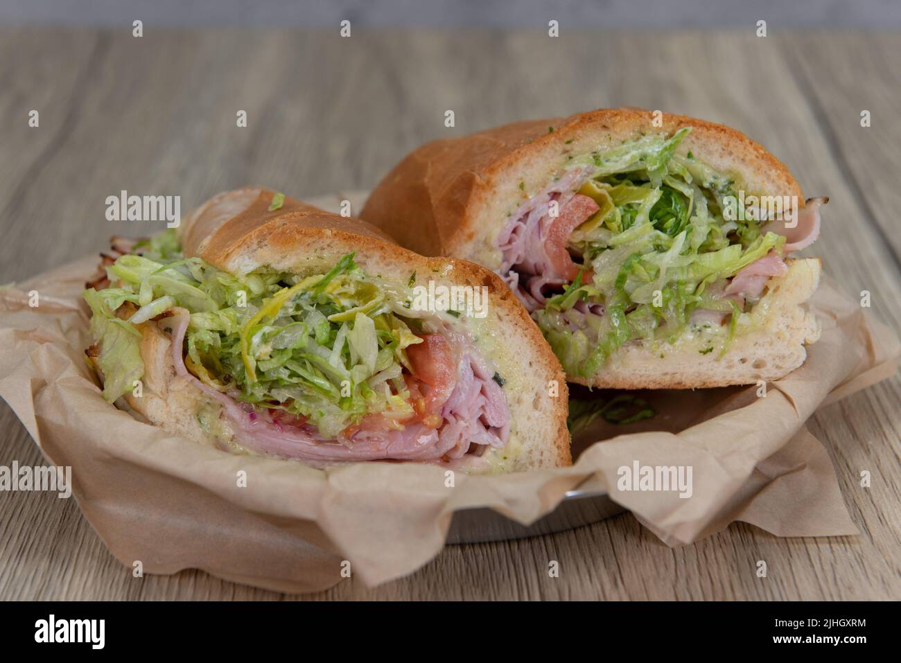 Loaded ham sandwich with provolone cheese, tomato, mayo, and red onion inside an Italian Roll for a hearty lunch meal. Stock Photo